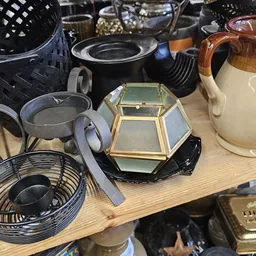 Assortiment huishoudartikelen op een tafel: vazen, pannen, manden, glaasjes en decoratieve items