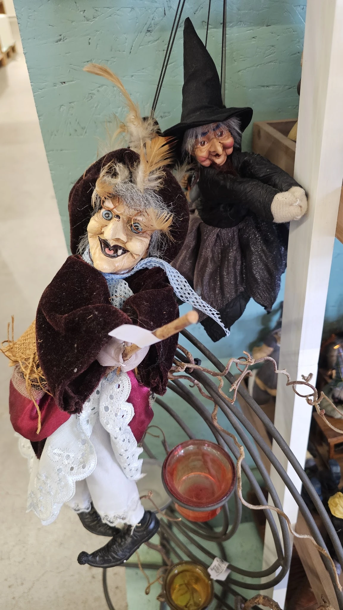 Close-up van een vintage pop/trol met grijze haren, blauwe ogen en donkere kledij in een vitrine
