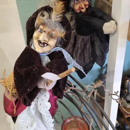 Close-up van een vintage pop/trol met grijze haren, blauwe ogen en donkere kledij in een vitrine