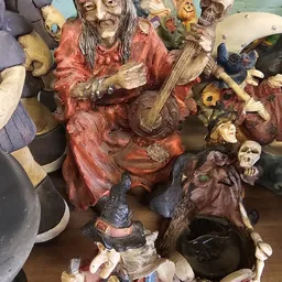 Verzameling decoratieve beelden en figuren met muziekinstrumenten, waaronder rood en bruin gekleurde religieuze of traditione