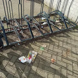 Buiteninrichting met metalen fietsenrekken en afval op straatsteens