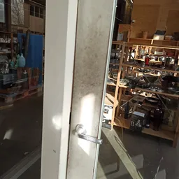 Zicht op glazen deur en winkelinterieur met houten stellingen en spullen op achtergrond