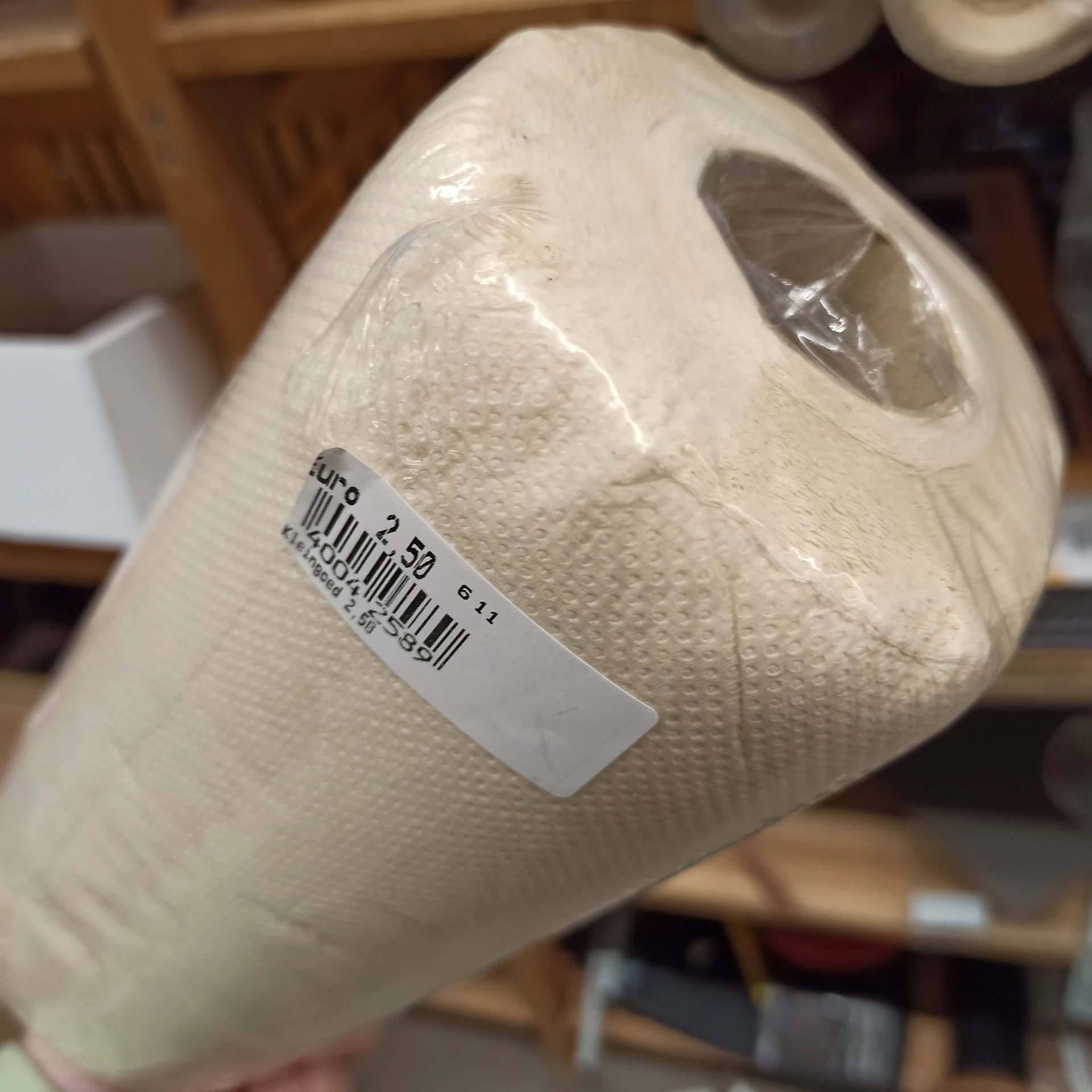 Rol witte papieren handdoeken met prijssticker, plastic verpakking