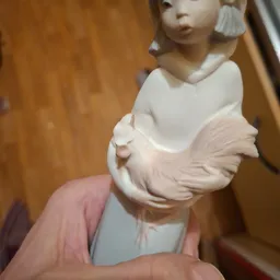 Close-up van een wit porseleinbeeldje van een vrouw in roze jurk