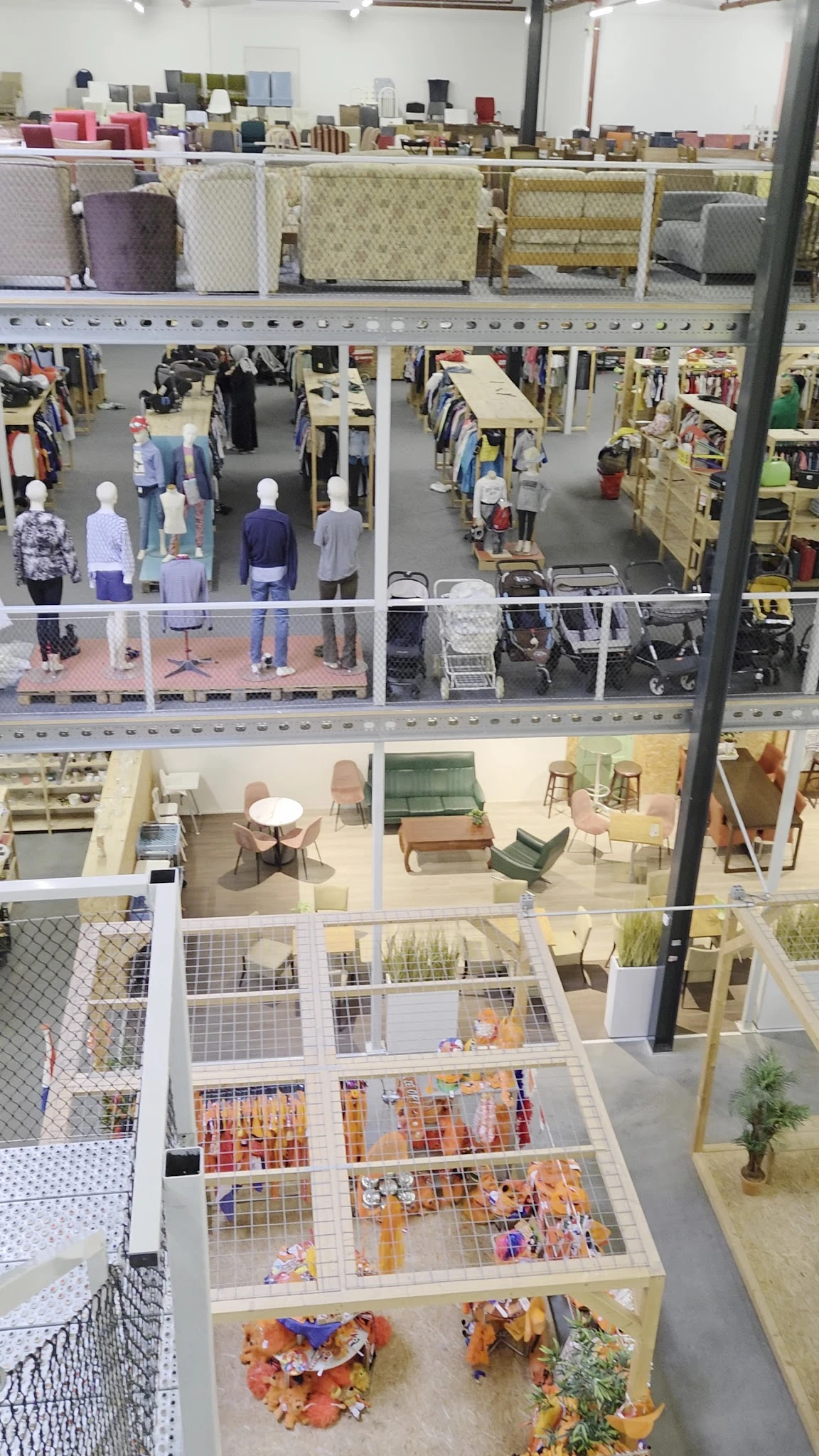 Overzicht van meerdere winkelverdiepingen met mannequins, winkelrekken, huisraad en meubels