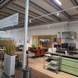 Winkelvloer met groene keukenkasten, huismeubilair, decoratiestukken en diverse gebruiksartikelen in kringloopwinkel.