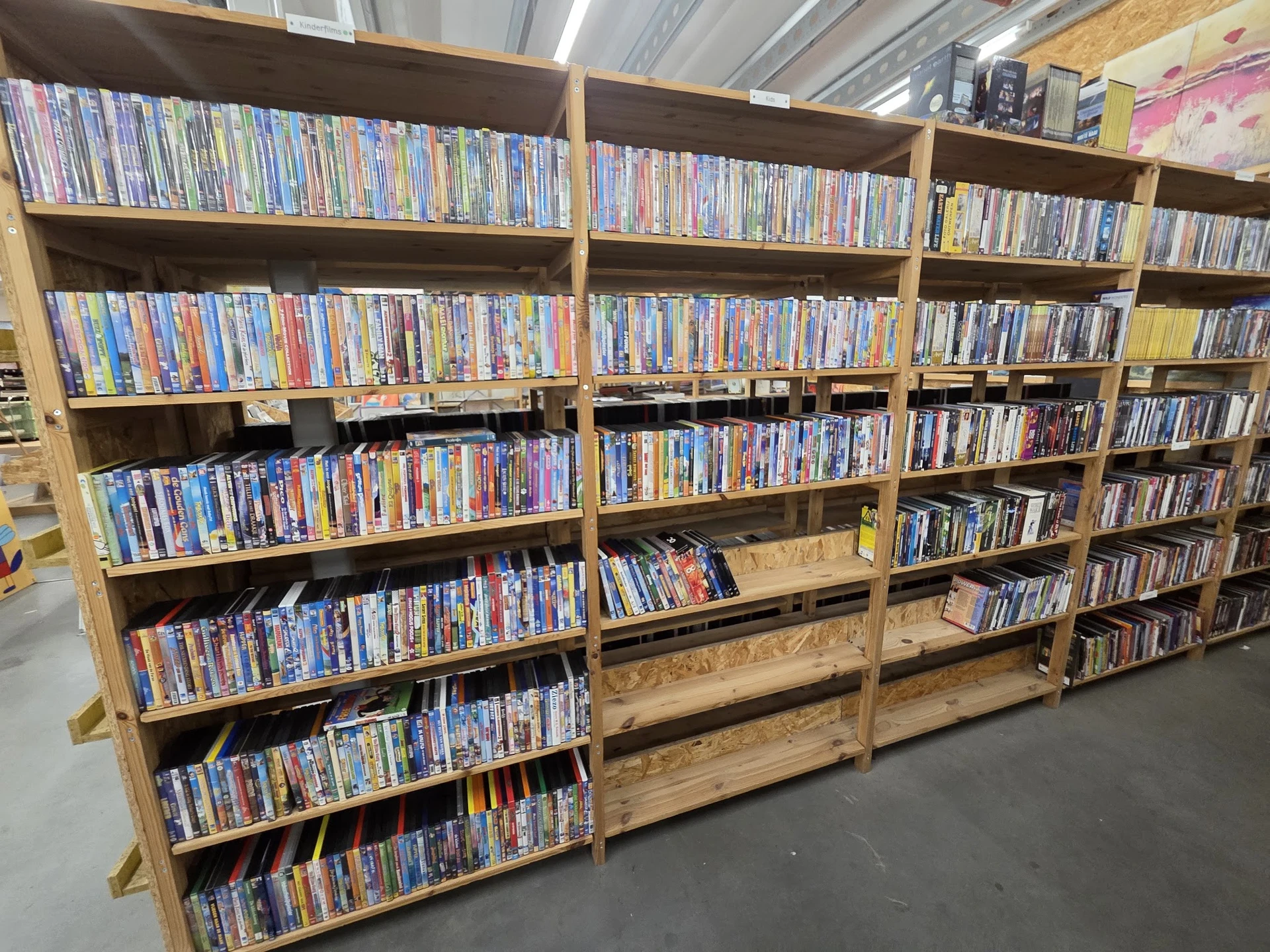 Houten stellingen vol met dvd's en blu-rays netjes uitgestald in rijen