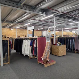 Ruime winkelhal met kledingrekken, spiegels en houten displays, LED-verlichting aan plafond