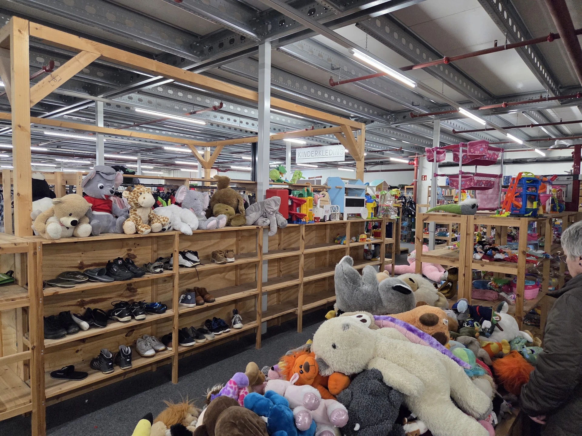 Winkelvloer met houten stellingen vol speelgoed, knuffels, schoenen en diversen gebruiksartikelen