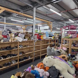 Winkelvloer met houten stellingen vol speelgoed, knuffels, schoenen en diversen gebruiksartikelen