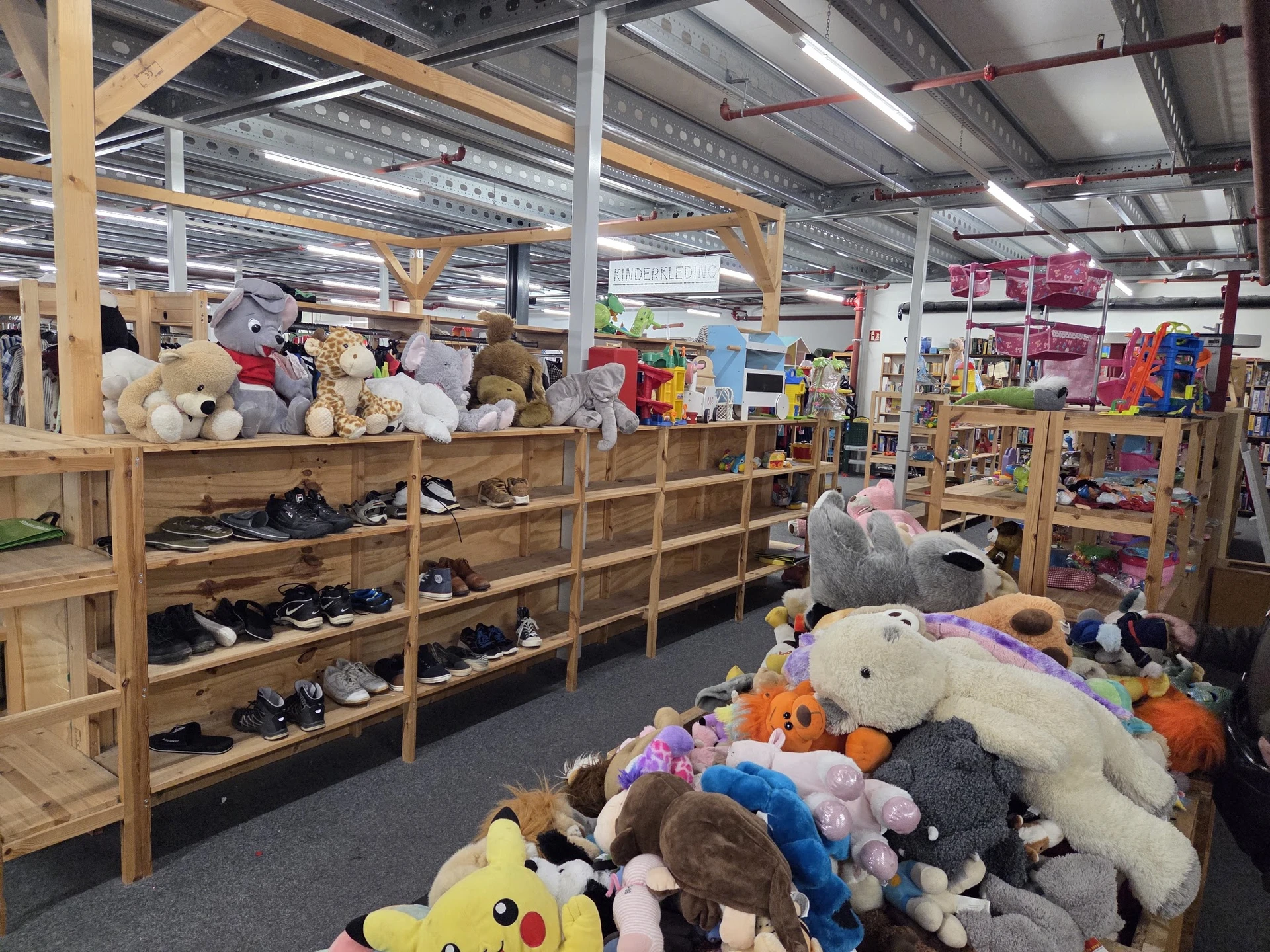 Winkelinterieur met houten stellingen vol speelgoed, knuffels en schoenen