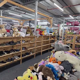 Winkelinterieur met houten stellingen vol speelgoed, knuffels en schoenen