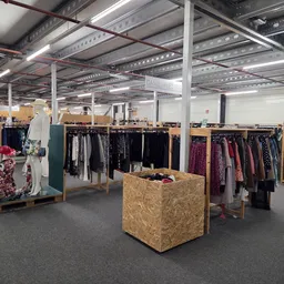 Winkelvloer met kledingrekken en uitstalling in een kringloopwinkel