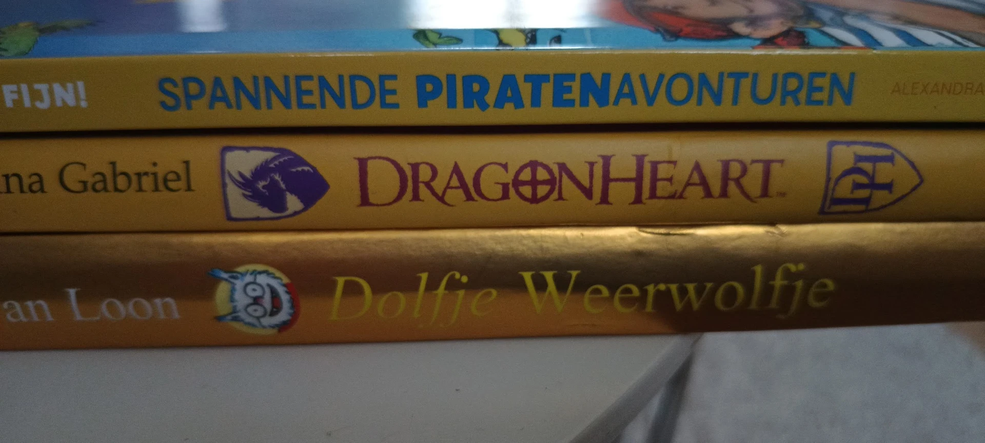 Drie boeken gestapeld met gekleurde ruggen, waaronder titels als 'Dragenheart' en 'Dolfje Weerwolf'