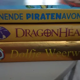 Drie boeken gestapeld met gekleurde ruggen, waaronder titels als 'Dragenheart' en 'Dolfje Weerwolf'