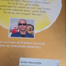 Boekpagina met Nederlandse tekst en foto van man met zonnebril en twee speelgoedpoppen