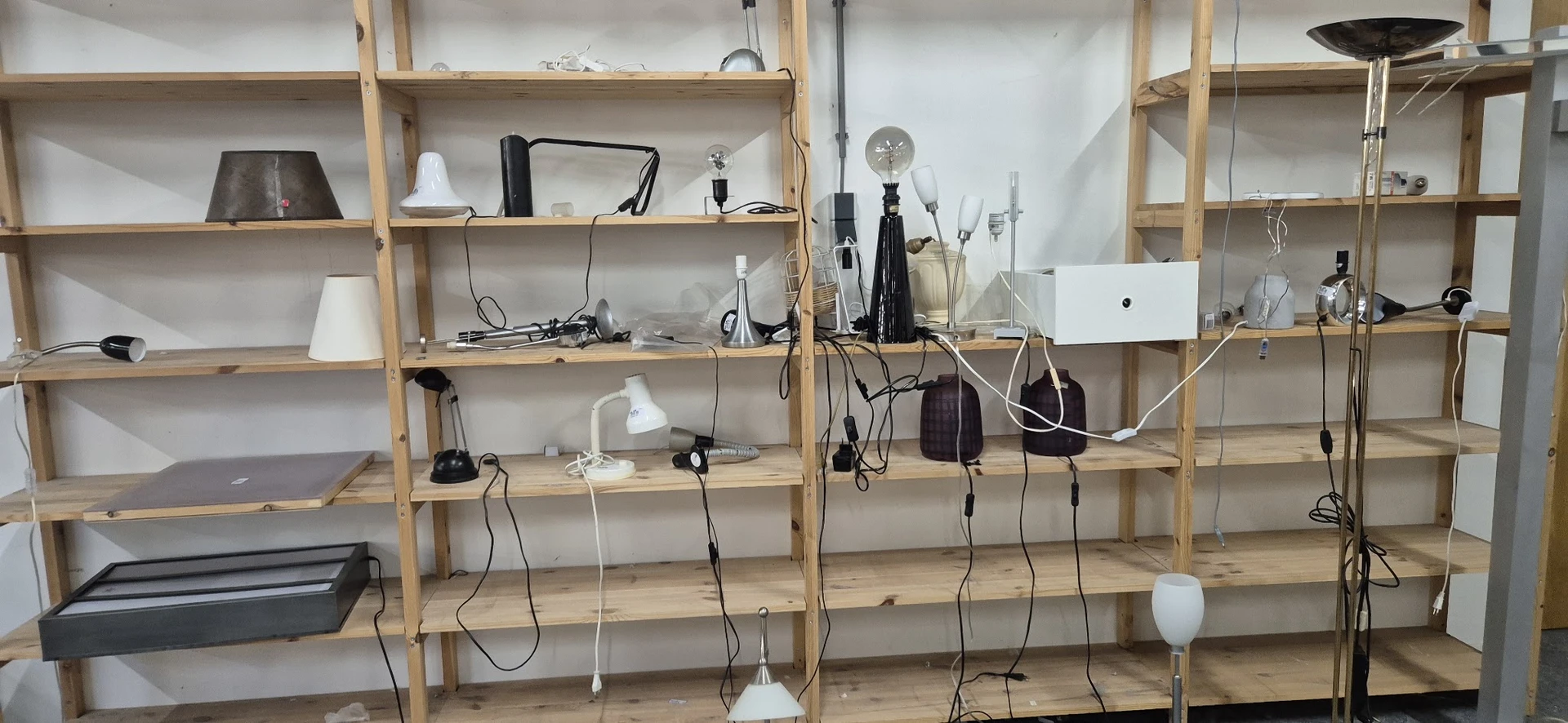 Houten stellingen met elektronische apparatuur en kabels, waaronder microfoons, lampen en computeronderdelen