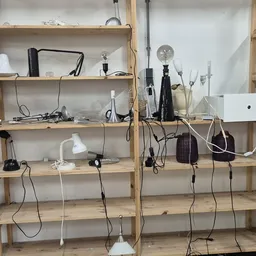 Houten stellingen met elektronische apparatuur en kabels, waaronder microfoons, lampen en computeronderdelen