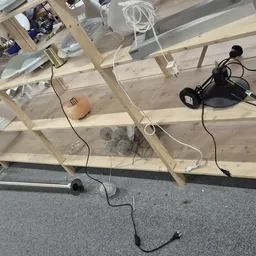 Werkruimte met houten stellingkast, elektrische apparaten en kabels op betonvloer