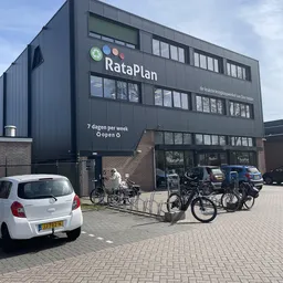 Voorgevel van RataPlan kringloopwinkel met donkere gevel, grote ramen, winkelentree en fietsenstalling met fietsen