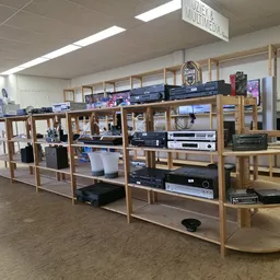 Houten stellingsysteem met audiovisuele apparatuur, televisies en elektronische items in kringloopwinkel