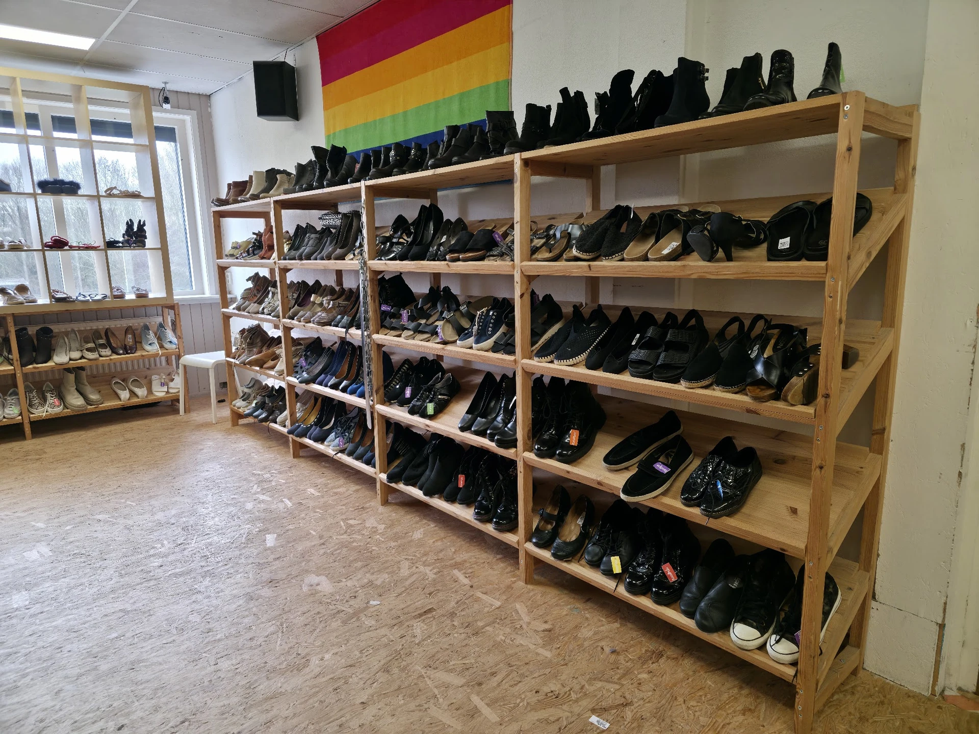 Houten stellingen vol met zwarte schoenen en laarzen in verschillende maten en stijlen
