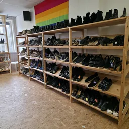 Houten stellingen vol met zwarte schoenen en laarzen in verschillende maten en stijlen