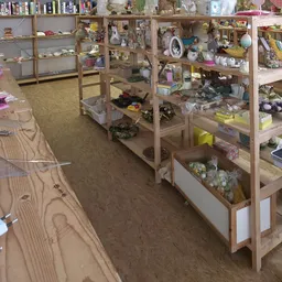 Winkelvloer met houten stellingen vol spullen, roze bakken en diverse tweedehands artikelen