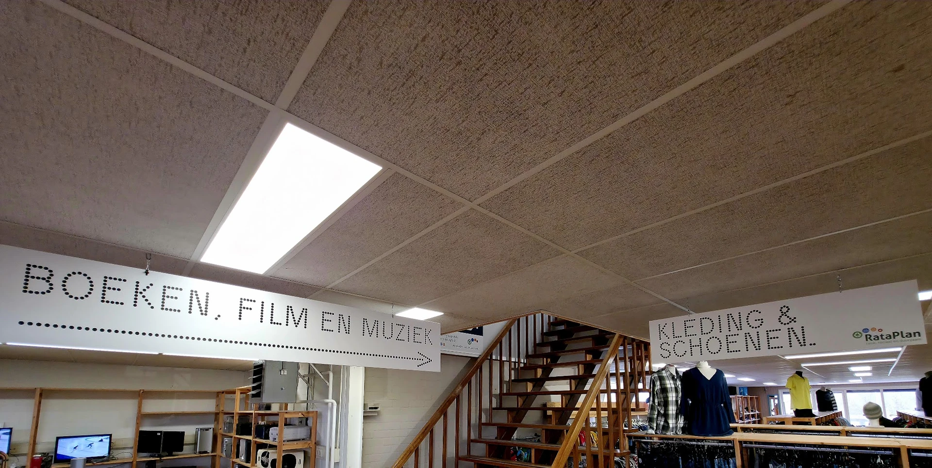 Winkelinterieur met plafond, trappenhuizen en borden met afdulingsaanwijzingen