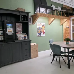 Ingerichte ruimte met zwarte buffetkast, eettafel met stoelen en groene muur met houten details