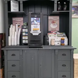 Grijze kast met open kastjes,DisplayScreens en advertenties voor Spanish Coffee en Catalan, met kopjes, kranten en andere spu
