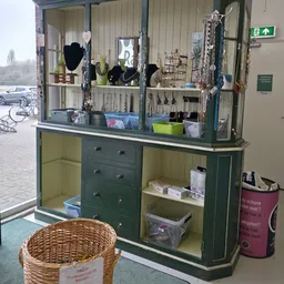 Groen meubelstuk met spiegels, sieraden en accessoires op display, met open kasten en laden vol opgestelde items