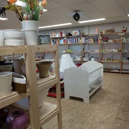 Winkelvloer met houten stellingen, babykribben, boeken, speelgoed en huishoudartikelen