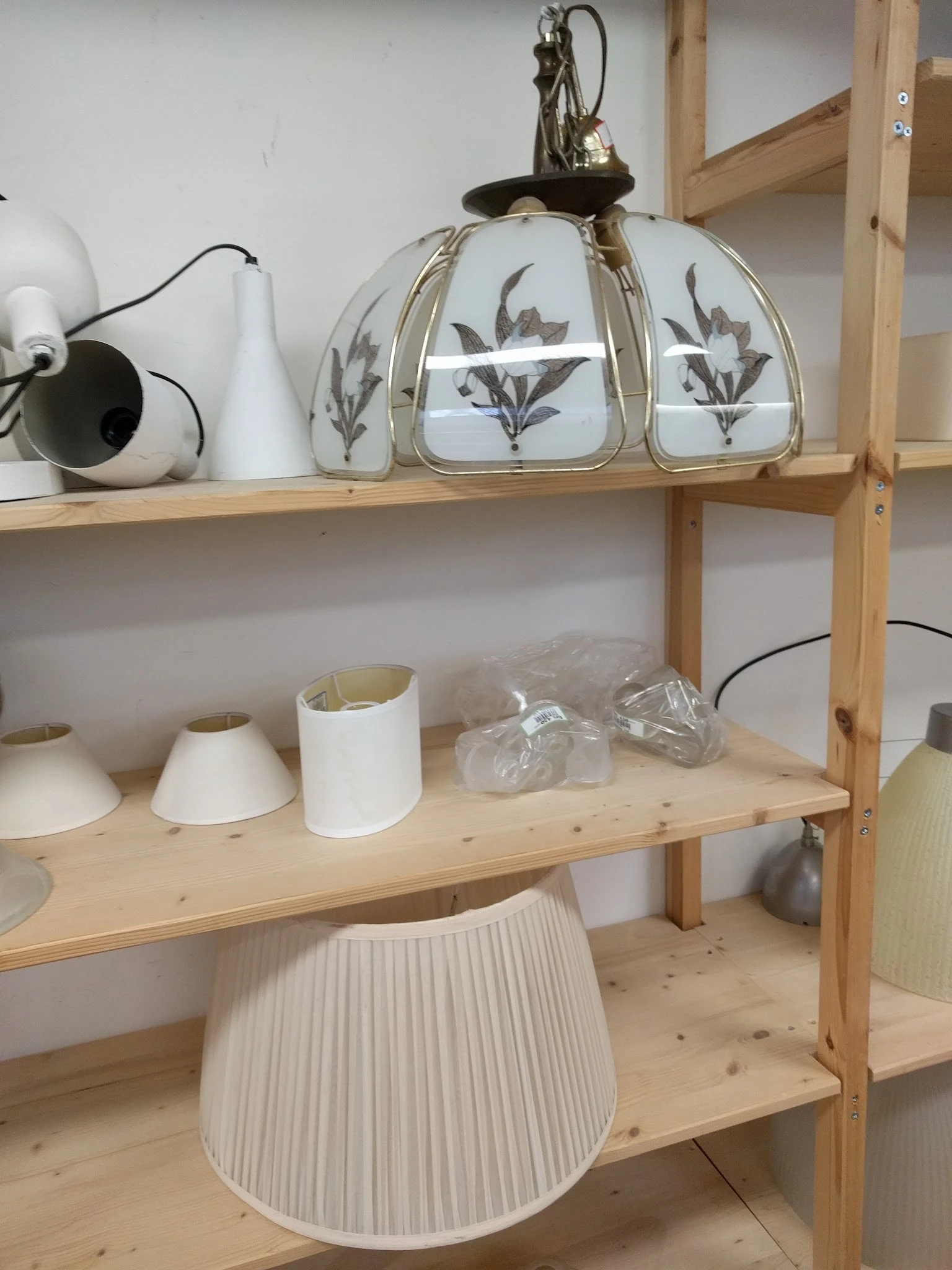 Houten stellingkast met serviesgoed: witte lampen, decoratieve potten met patroon en verpakte items