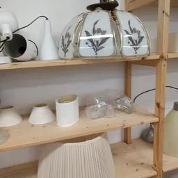 Houten stellingkast met serviesgoed: witte lampen, decoratieve potten met patroon en verpakte items