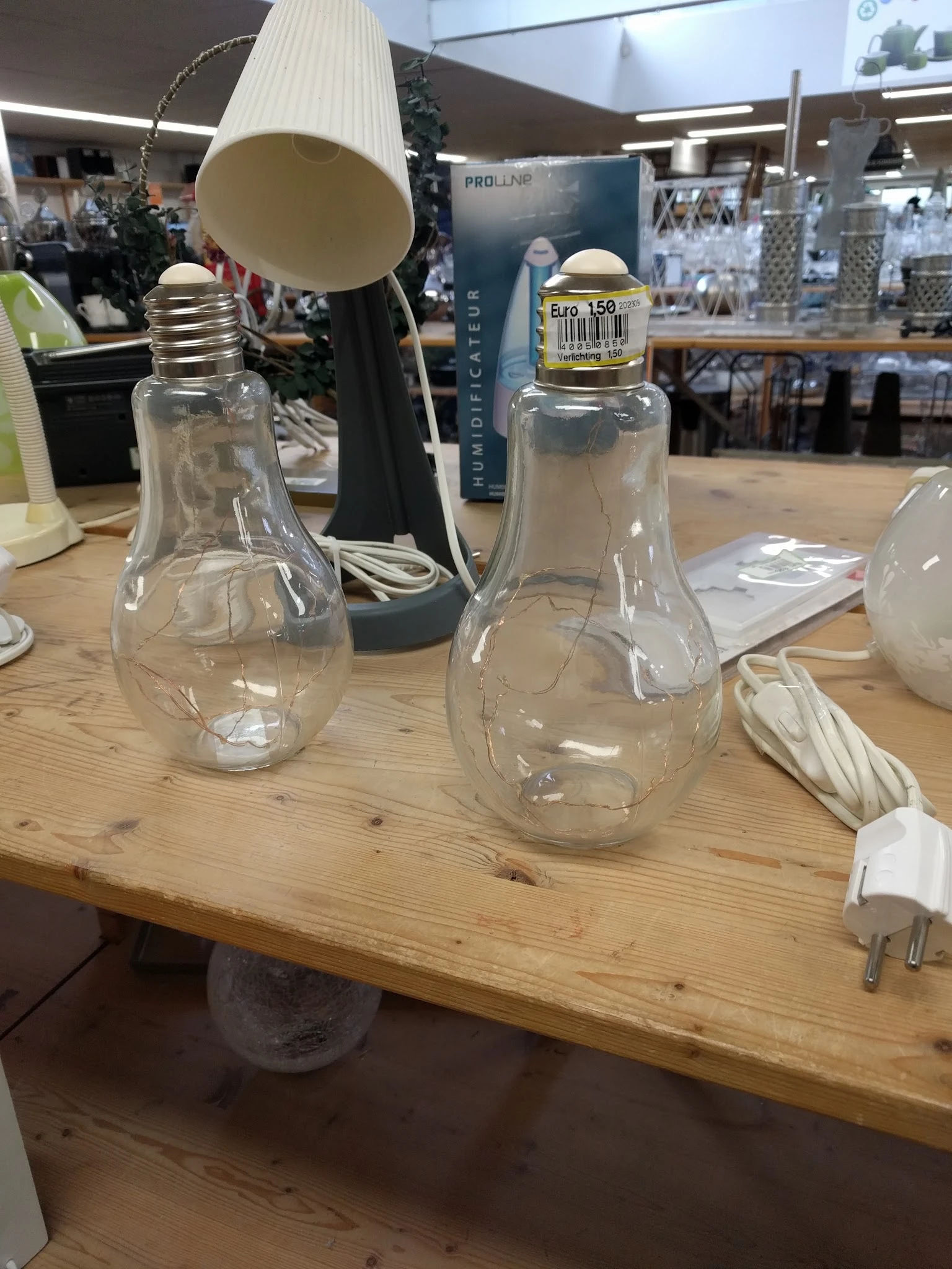 Twee glazen lampenkappen in vorm van gloeilampen op houten tafel