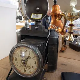 Close-up van een vintage camera met bijbehorende klok op houten display