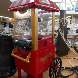 Rode vintage popcornmachine met gele details en decoratieve sterren op de voorkant