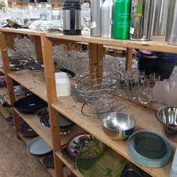Houten stellingen met keukengerei: glazen, pannen, servies en een drainagerek netjes uitgestald