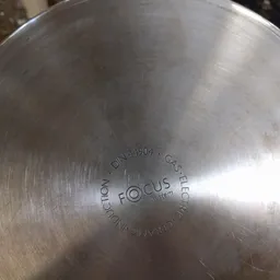 Close-up van een metalen deksel met gravering 'FOCUS' en 'DIN 14904' zichtbaar