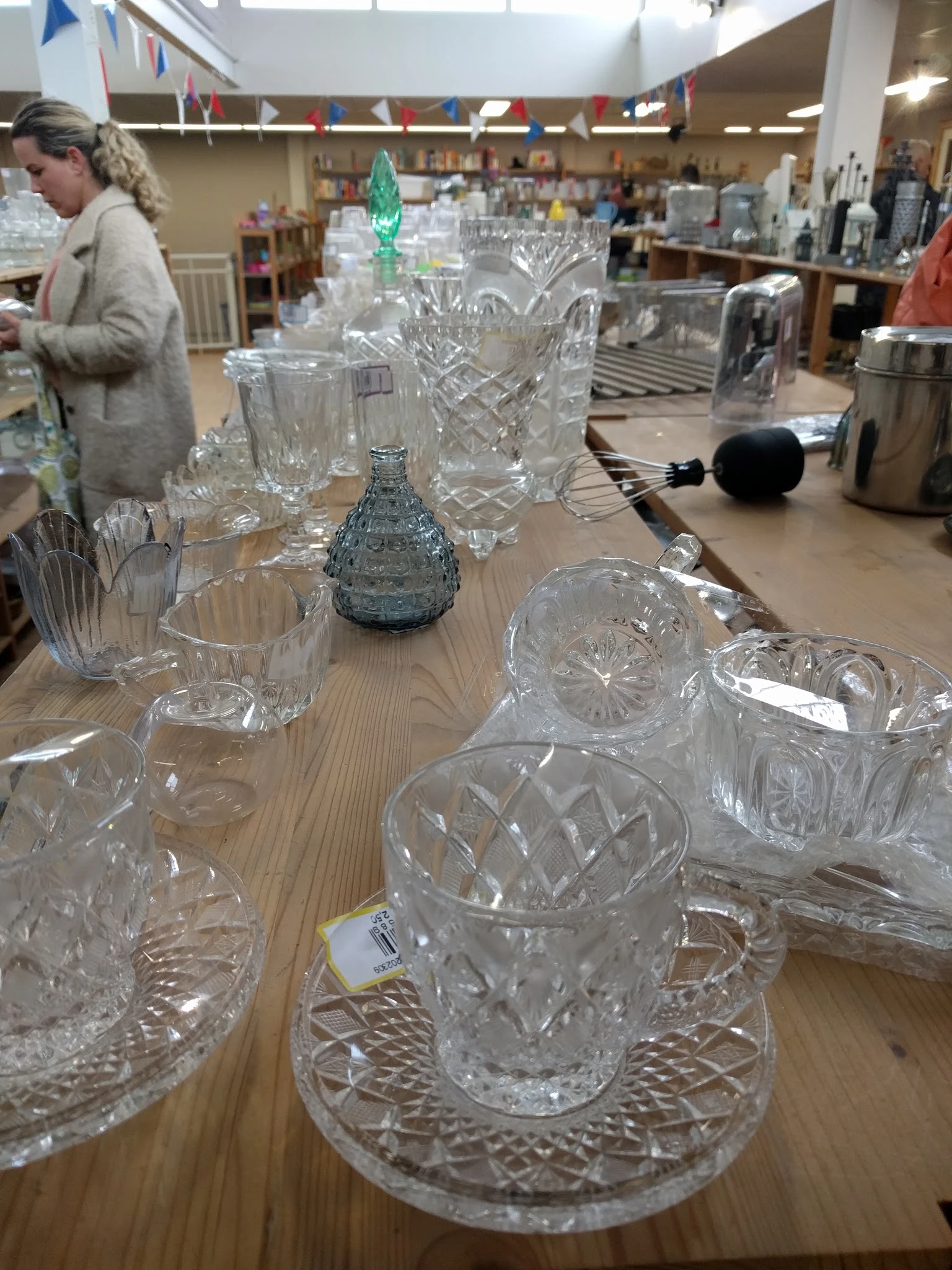 Uitgestalde kristallen glazen en vazen op een houten tafel in de winkel