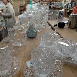 Uitgestalde kristallen glazen en vazen op een houten tafel in de winkel