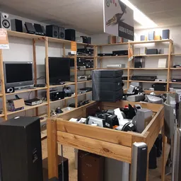 Houten stellingen met elektronische apparatuur en onderdelen in een kringloopwinkel