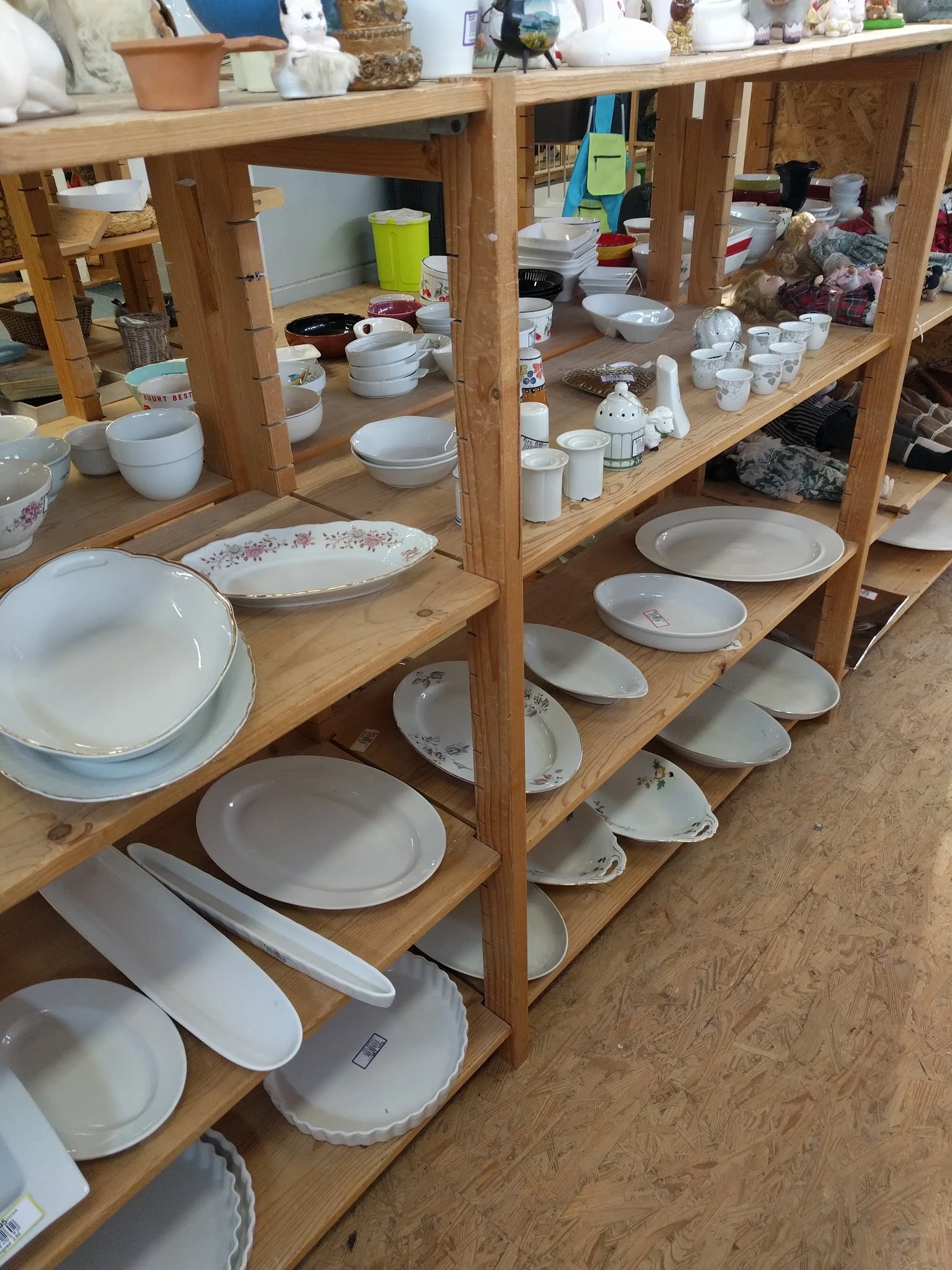 Houten stellingen met een uitgebreide verzameling wit servies, borden en schaaltjes