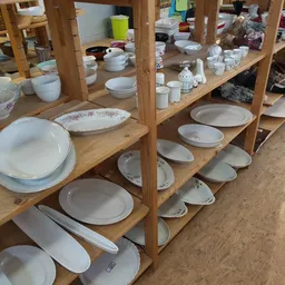 Houten stellingen met een uitgebreide verzameling wit servies, borden en schaaltjes