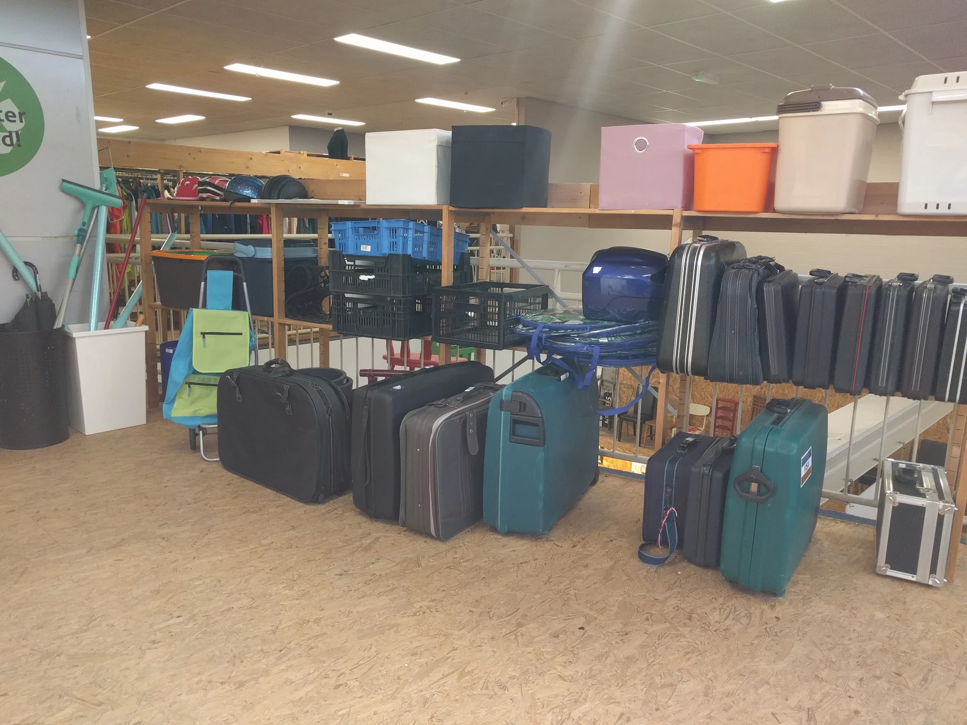 Uitgestalde koffers en tassen in verschillende kleuren en maten op de kringloopwinkelsvloer