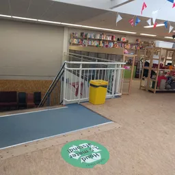 Winkelvloer met speeltoestellen, boekenkast, decoratie en een groene cirkel op de vloer