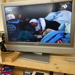 Screenshot van een televisie-uitzending met mensen in bedden