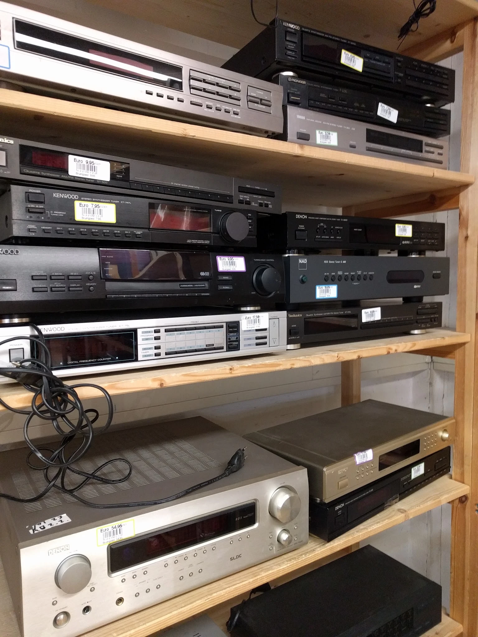 Tweedehands elektronische apparatuur in een stellingkast: versterkers, tuners en andere audio-equipement
