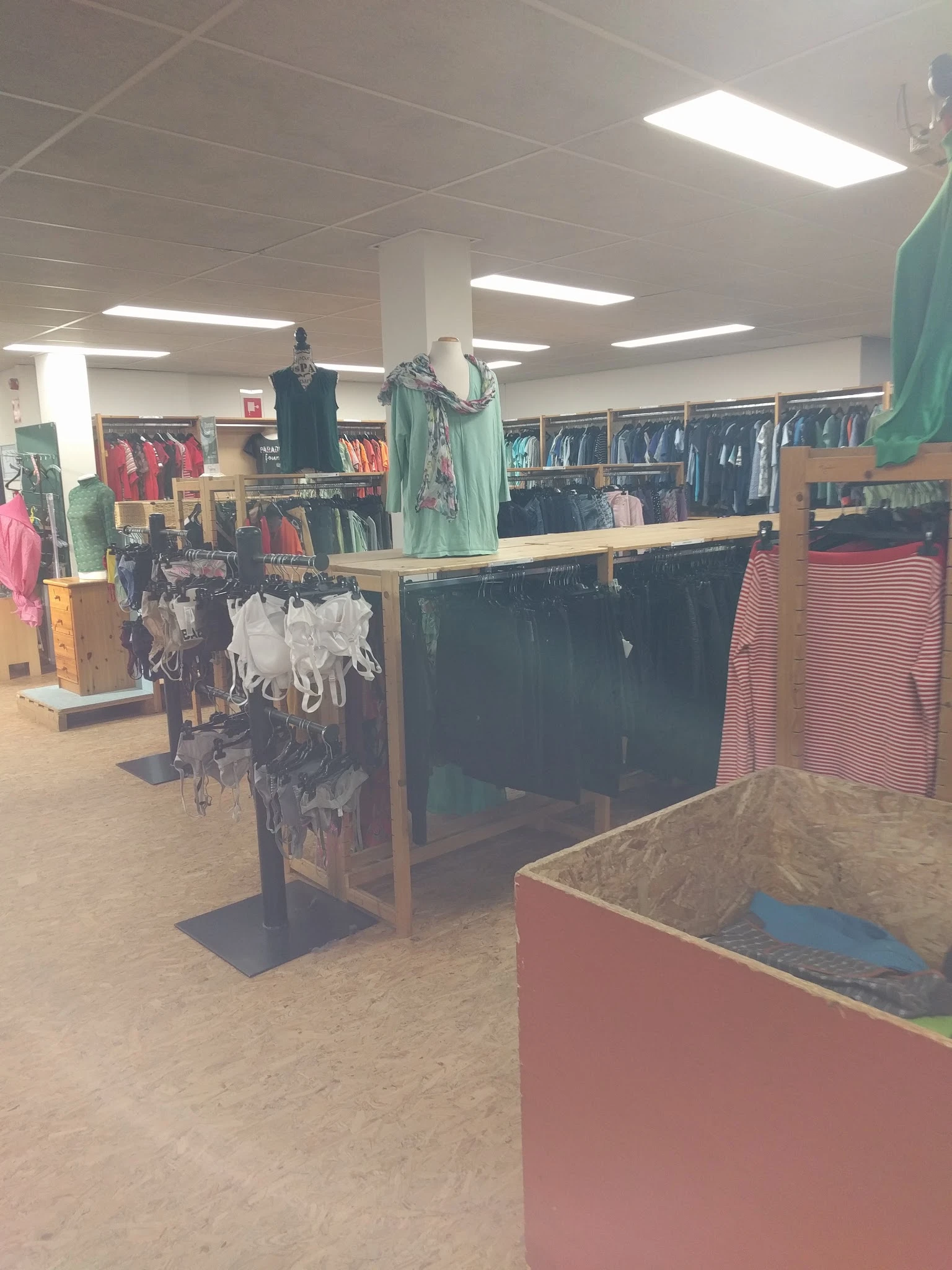 Winkelinterieur met kledingrekken, uitstalkast en mannequins met kleding